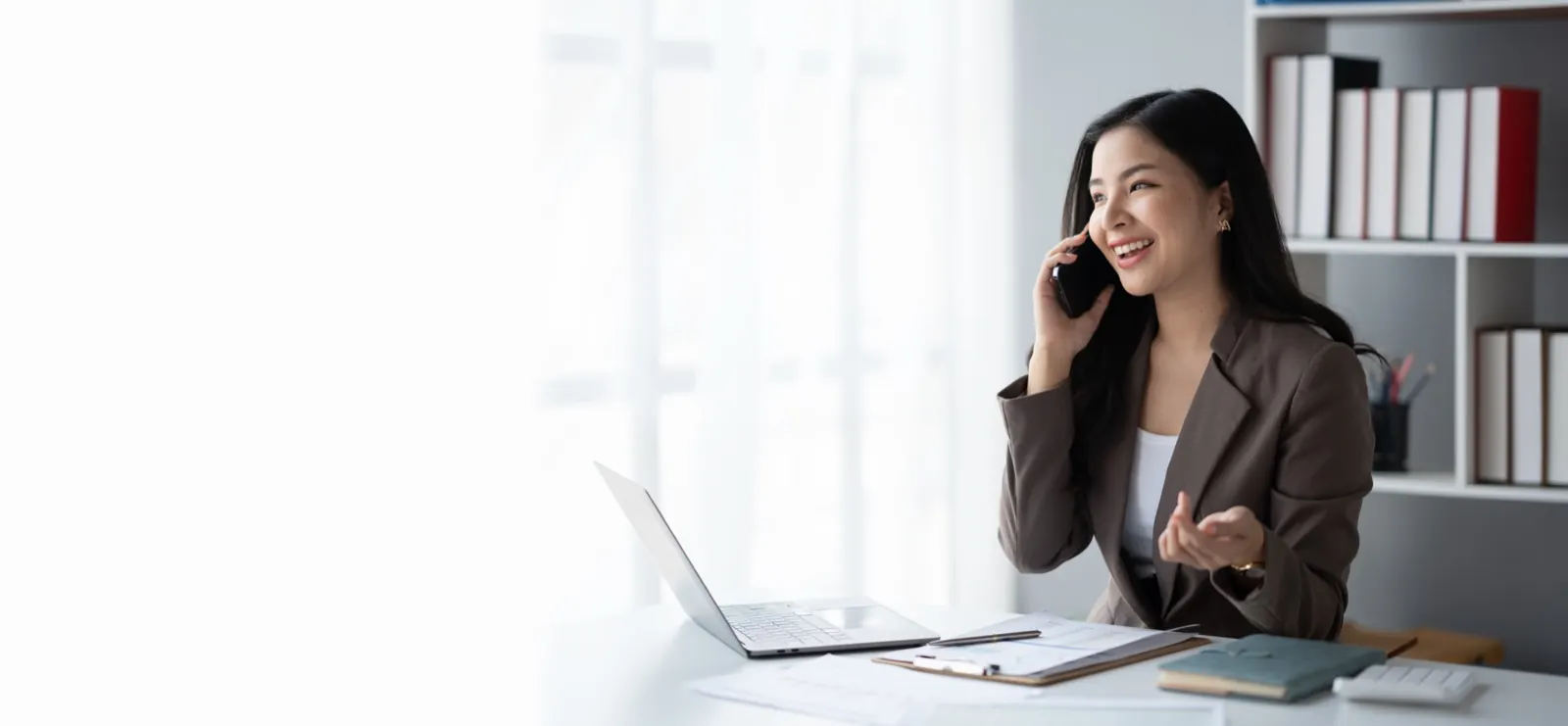 Professional smiling on a phone call at her desk