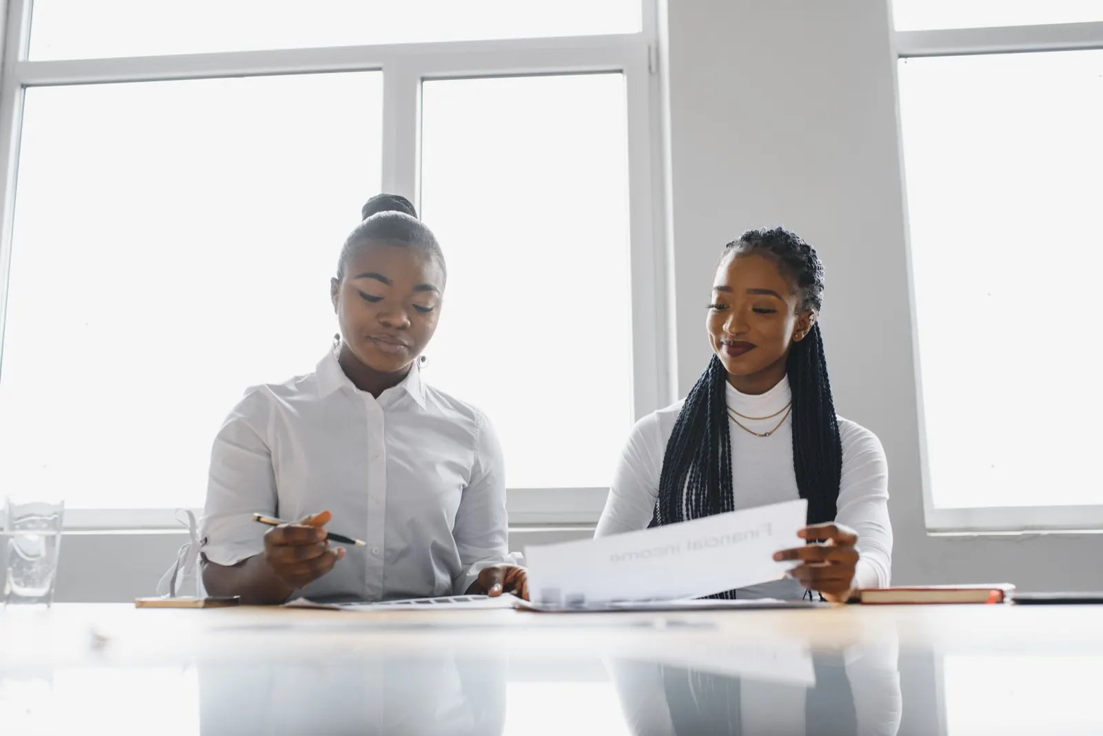 Two professionals reviewing financial documents at a bright office table